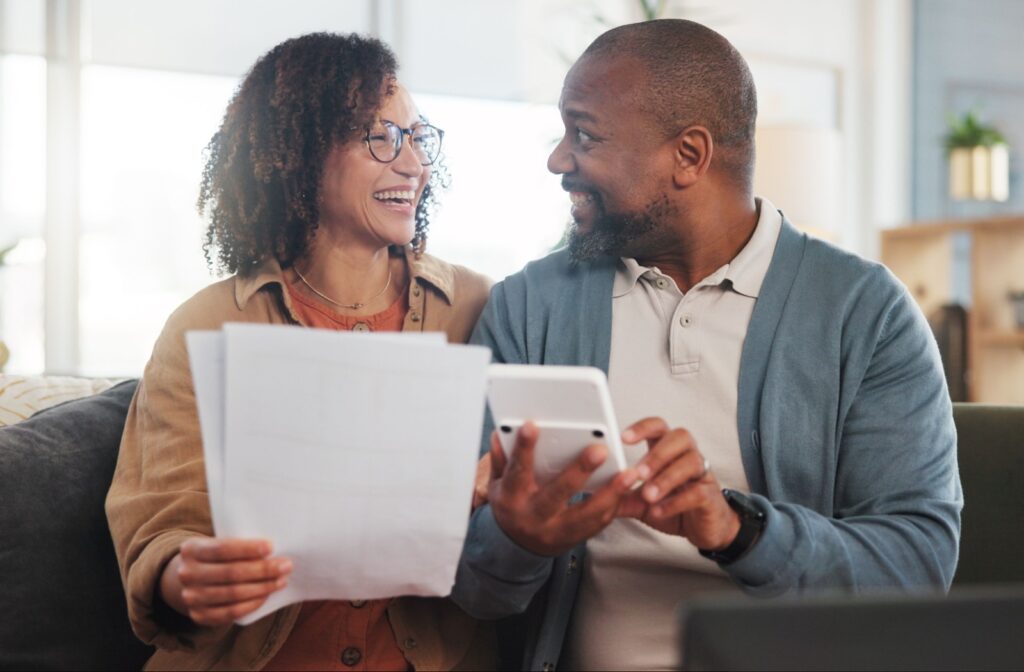 A middle aged couple calculating their finances and smiling as they plan their retirement